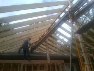 Rafters going up over a new addition with a worker on the wall in Pawling