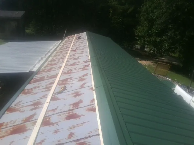 Old rusted panels beside newly installed green metal roofing — Wind Damage Roof Repair by Roofing Brothers in Pawling