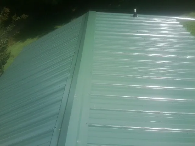 New green metal panels meeting at the ridge of a roof — Flat Roof Repair work by our crew in Pawling