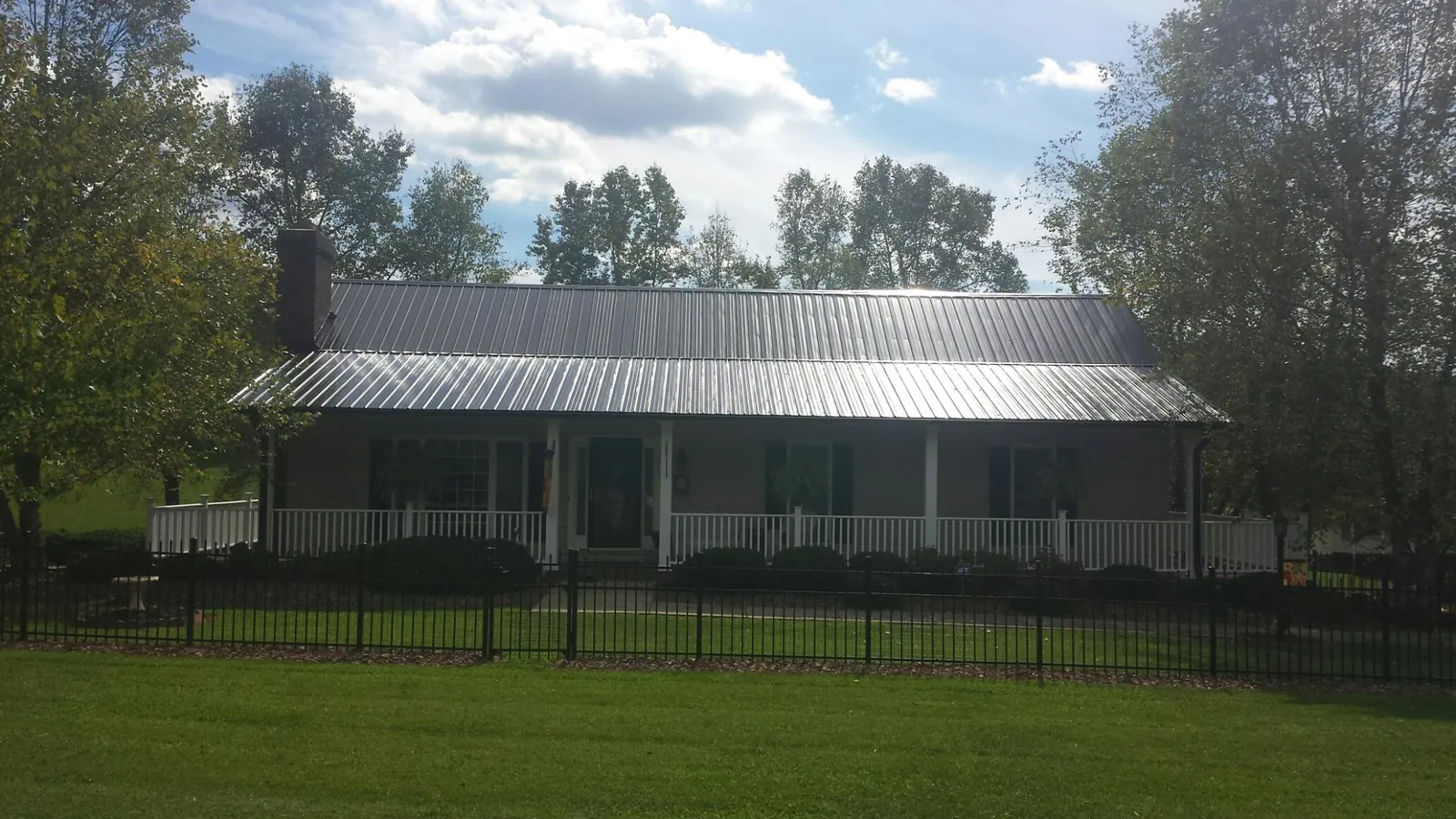 Gray metal roof on a brick ranch with a full width front porch — Gutter Guard Installation work by our crew in Pawling