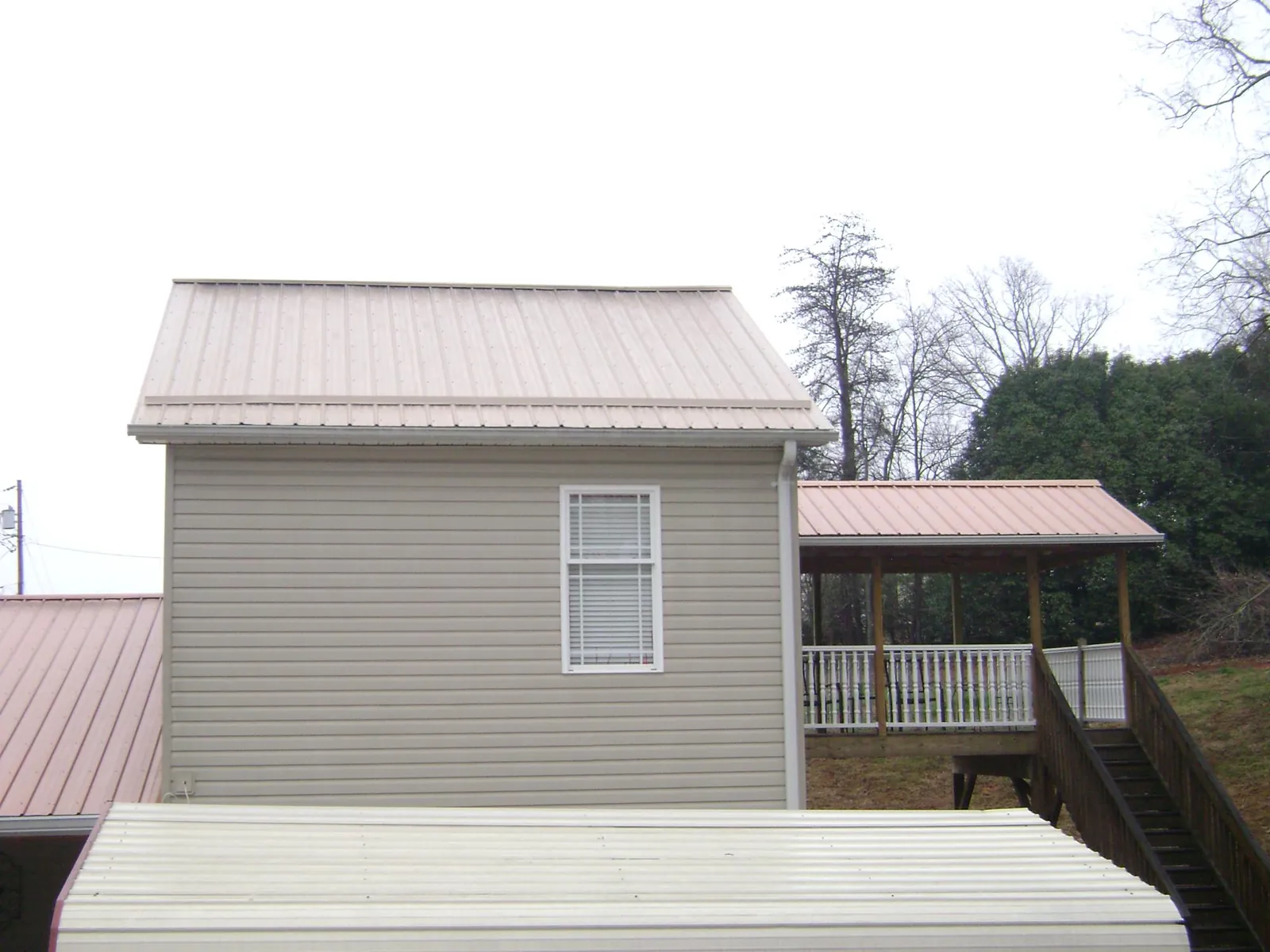 Tan metal roofs on a two story addition and attached porch, from a Roof Replacement job in Pawling