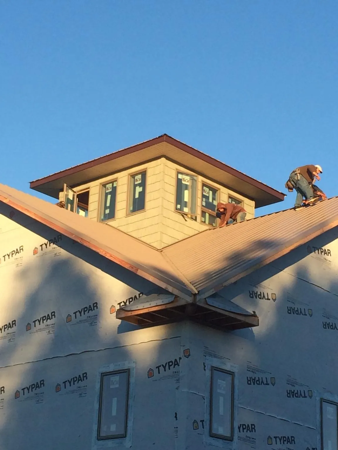 Roofers working around a rooftop cupola on a new metal roof at sunset — Roof Waterproofing in Pawling by Roofing Brothers